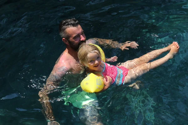 Un padre con su pequeña hija nadando en el mar — Foto de Stock