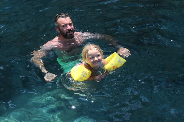 Un padre con su pequeña hija nadando en el mar — Foto de Stock