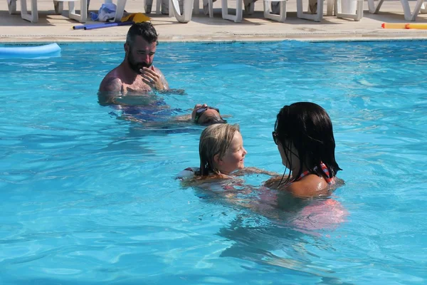 Una familia joven divirtiéndose en una piscina — Foto de Stock