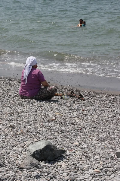 Een oude Turkse dame in traditionele kleding op het strand — Stockfoto