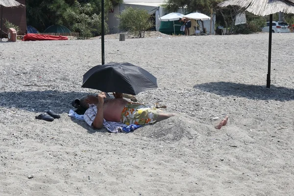 Um turco local deitado na areia sob um guarda-chuva — Fotografia de Stock