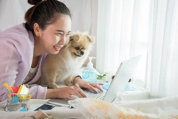 Woman and dog showing of happiness after shopping online with the life style New Normal for self quarantine during the outbreak Corona virus Disease (COVID-19).