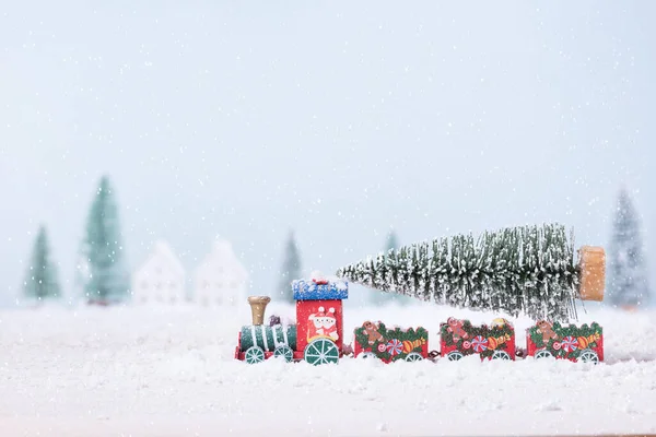 Christmas tree on toy train was running through the snow in the field of natural Landscape background.