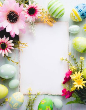Mutlu Paskalya günleri. Renkli yumurtalar ve çiçek süslemeleri. Ahşap arka planda..