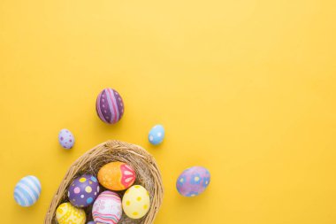 Mutlu Paskalya Günü dekorasyonu. Yuvadaki renkli yumurtalar. Kağıt zemin üzerinde..