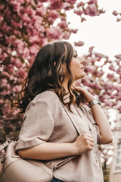 Arka planda sakura olan portait. Elinde bir sırt çantası var..