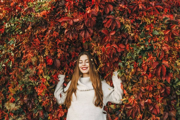 Mutlu genç kadın büyük bir sarmaşık duvarında yatıyor..