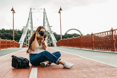 Pretty woman with long hair is photographing while sitting on th clipart