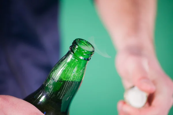 Man opens a bottle of beer in studio — Stock Photo, Image