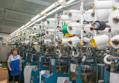 GRODNO, BELARUS - 14 ARALIK 2014. Kadın iplik üretimi için dokuma makinelerinde çalışıyor. Yüksek kalite fotoğraf