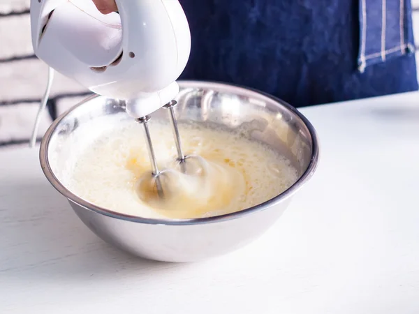 Mélange de crème d'oeuf dans un bol avec un mélangeur à moteur — Photo