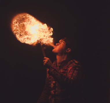 Ateş sanatçısı karanlıkta ateş püskürtür.
