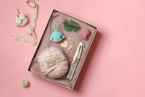 Hygge box with knitting accessories, amigurumi toy, a ball of pink yarn and a sign with the signature Hygge time