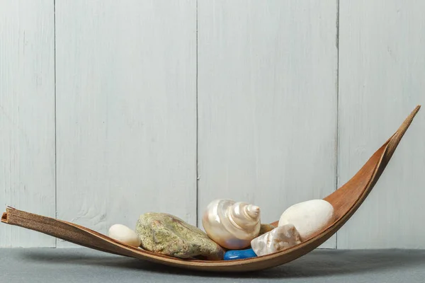 Decoration for the interior. Sea stones and pieces of marble, a mother-of-pearl shell on a wooden stand.