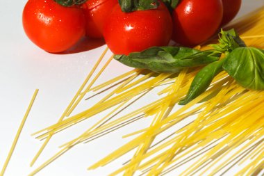 Lezzetli makarna hazırlama konsepti. Dağınık spagetti, domates ve fesleğen. Bolonez makarna yapmak için gerekli malzemeler