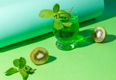 Kivi, limon, tarhun ve naneli tropikal kokteyl konsepti. Karbonatlı doğal içecek, yakın plan yeşil arka plan, sert gölgeler..