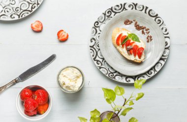 Fresh summer breakfast. Ricotta and strawberry sandwich on a gray patterned plate. Overhead, on a gray wooden background
