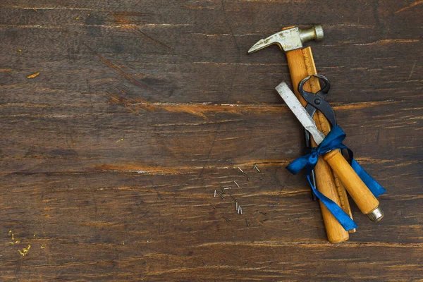 Herramientas de carpintería atadas con una cinta de regalo azul. Sobre la cabeza, sobre un fondo de madera rugosa, horizontal con espacio. El concepto de un regalo para papá — Foto de Stock