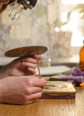 Dürbünlü bir kadın restoratör, bir fırçayla ikonun üzerine eğilmiş. Resimli şaheserlerin restorasyonu, müze