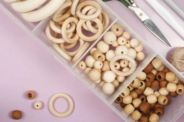 A set of wooden beads, rings for making crafts for children, jewelry, rattles, amigurumi. In a plastic organizer, close-up, top view, copy of the space, horizontal