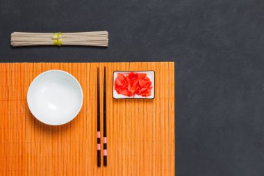 Japon karabuğday erişteli soba pişirme kavramı. Soba sos, et suyu, salata, poka, sıcak et ve vejetaryen yemeklerde kullanılır. Bir demet erişte, zencefil, yemek çubuğu ve siyah arka planda bir kase çorba.