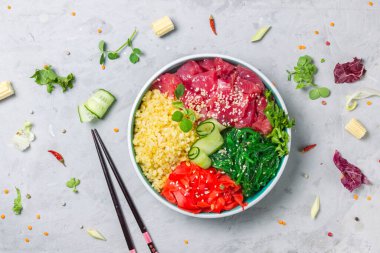 Ton balığı dilimleri, bulgur, chuka salatası ve turşulu zencefil. Dengeli, sağlıklı bir öğle yemeği. Ton balığı ve bulgur ile dürt. Üst manzara, yakın plan, yemek çubuklarıyla gri arka plan.