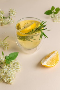 Elderflower şurubu, limon ve biberiyeli buzlu çay. Yakın plan, hafif arkaplan, dikey