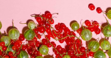 Yeşil bektaşi üzümleri ve kırmızı üzümler pembe arka plana saçılmış, sert ışık, yakın plan, boşluğun kopyası.