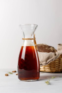 Koyu çavdar viskisi ya da biralı cam bir Jaguar. Hafif ahşap bir arka planda, arkasında çavdar ekmeği olan bir sepet. Boşluk ile dikey