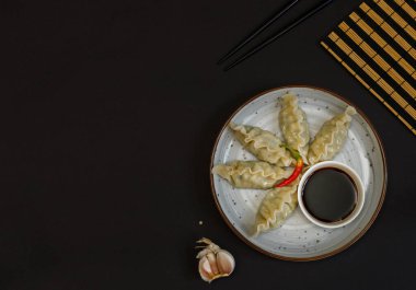 Gri tabakta soya soslu Gyoza köftesi. Çubuklu siyah bir arka planda. Üst görünüm, boşluğun kopyası, yatay
