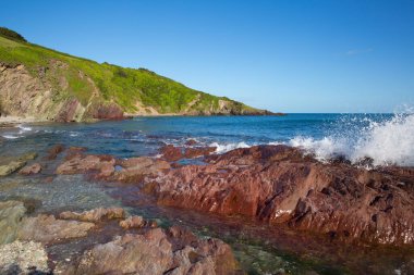 Talland Körfezi kırmızı renkli kayalar ve açık deniz Cornwall uk