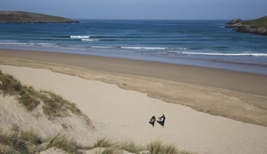 Sörfçü kamera Crantock koyun ve plaj North Cornwall İngiltere Newquay yakın ve mavi gökyüzü ve deniz ile ilkbaharda Güney Batı Yakası Yolu üzerinde yürüyüş