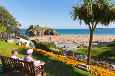 Tatilciler Tenby Pembrokeshire Galler İngiltere'de kale Beach'te yaz turistler ve ziyaretçiler ve mavi gökyüzü ile