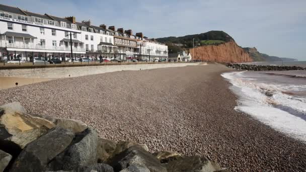 Vista para o leste Sidmouth praia Devon Inglaterra Reino Unido com ondas e seixos — Vídeo de Stock