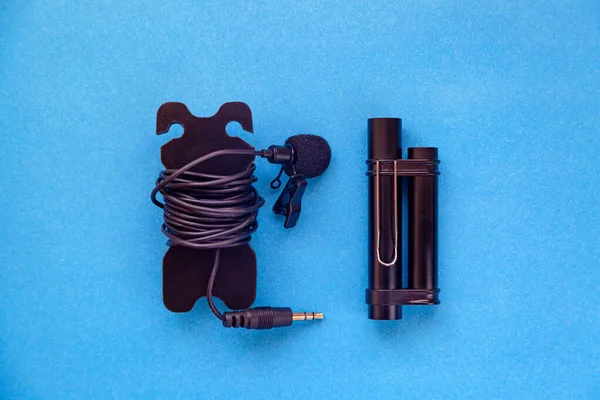 Lavalier microphone with long cable and power module. Blue background.