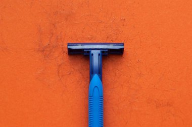 Turuncu arka planda mavi jilet ve tıraş edilmiş saç..