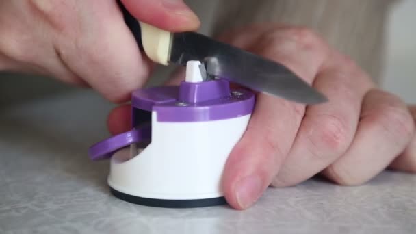 Seorang Pria Mengasah Pisau Dapur Dengan Rautan Atas Meja — Stok Video