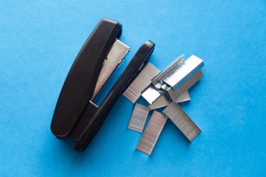 Bir takım ofis gereçleri ve mavi arka planda zımbalar..