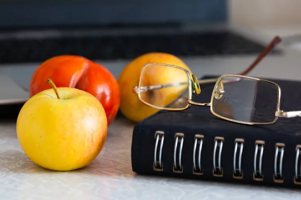 Lunch break at the workplace in the office. Fruit glasses notepad notebook.