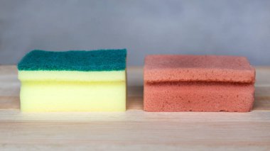 Ahşap arka planda yeni ve eski kirli bulaşık süngeri.