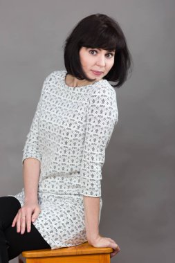 40 yaşında, siyah saçlı, fotoğraf stüdyosunda poz veren bir kadın..