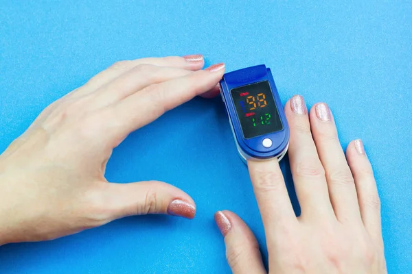 Oximeter on the finger of woman's hand, reading oxygen in human blood.