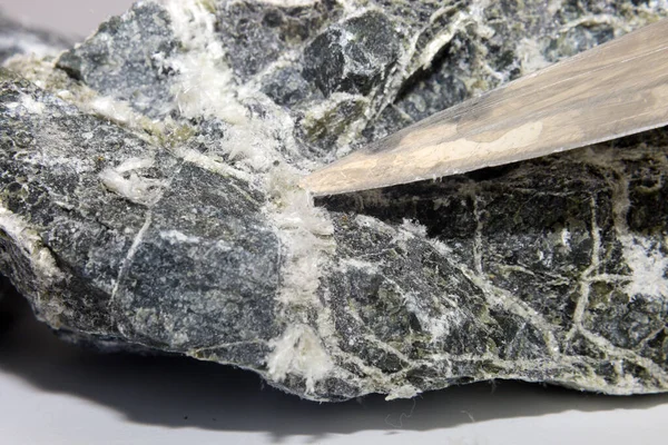 Bıçağın bıçağı taştan asbest liflerini çıkarır ve çıkarır..