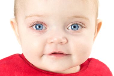Gözleri açık bir çocuk doğrudan beyaz bir arka plana bakar..