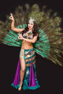 Lüks tavus kuşu tüyü elbisesi içinde doğulu bir kadın. Siyah arka plan..