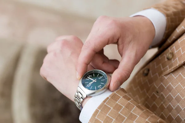 Male hands with a clock, brown plaid suit .