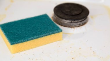 Bir temizlik süngeri kirli bir mutfak sobasının üzerinde yatar. Yakın plan.