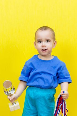 Sarı arka planda spor ödülleri olan sürpriz çocuk..