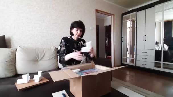 Mujer Abre Paquete Con Mercancías Mientras Está Sentado Sofá Casa — Vídeo de stock