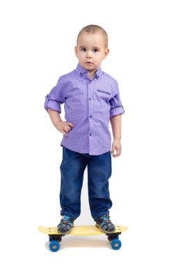 Gömlekli ve kot pantolonlu bir çocuk kaykayın üzerinde duruyor. İzole edilmiş.